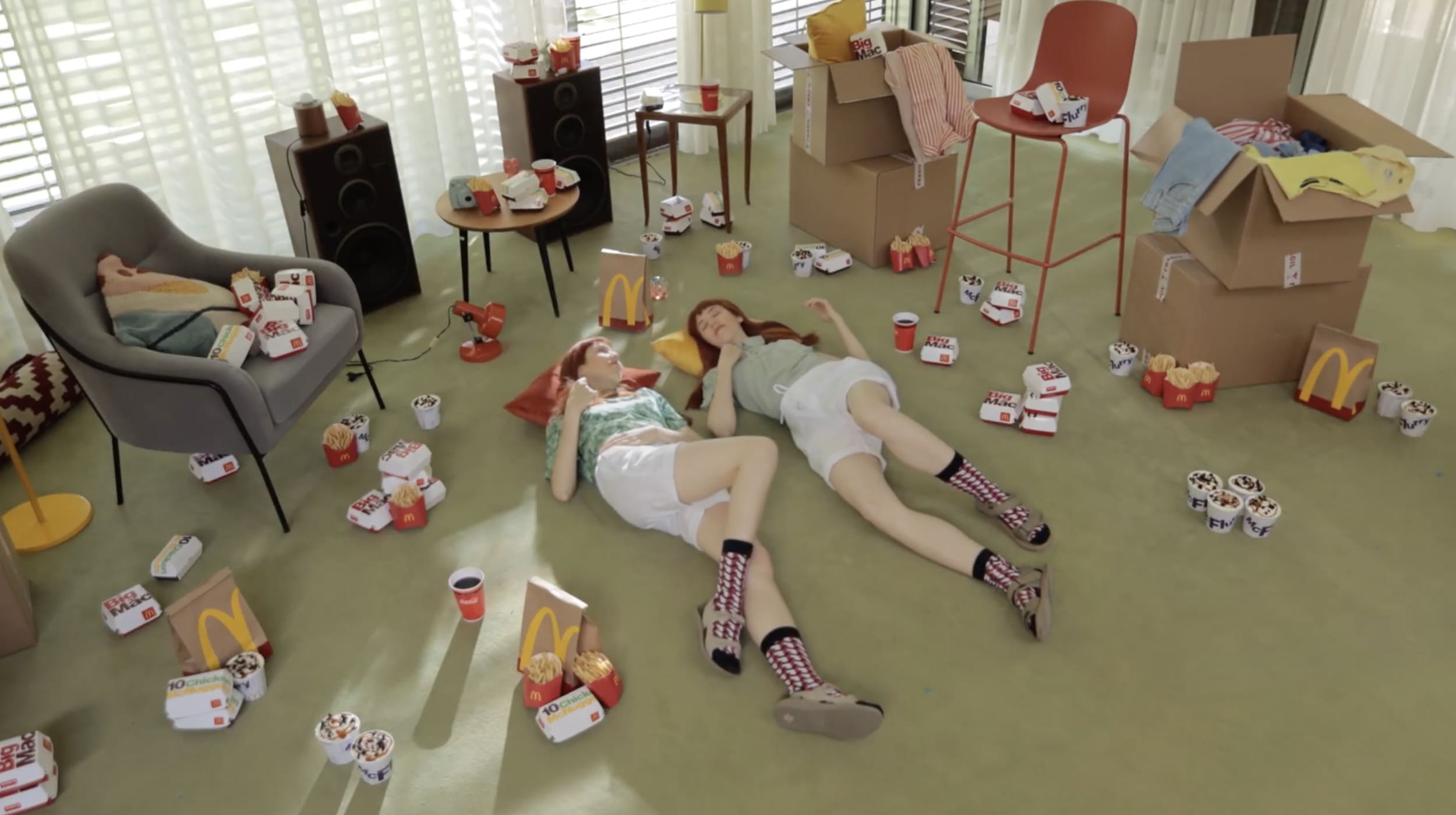 Dos chicas acostadas en el piso hablando rodeadas de combos de McDonald's.