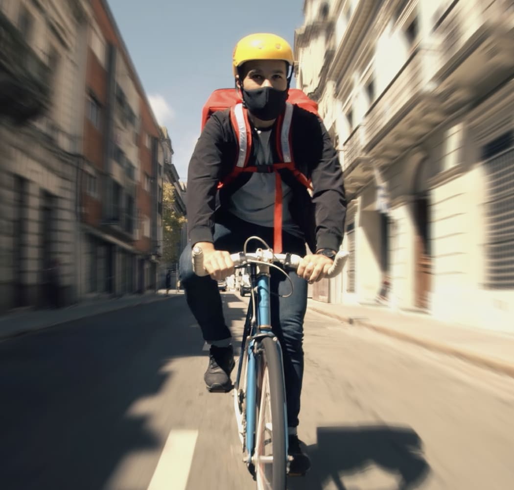 Chico del McDelivery en bicicleta llevando un pedido.