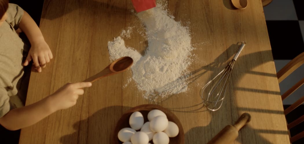 Mesa de cocina con harina desparramada y utensillos de cocina y huevos.